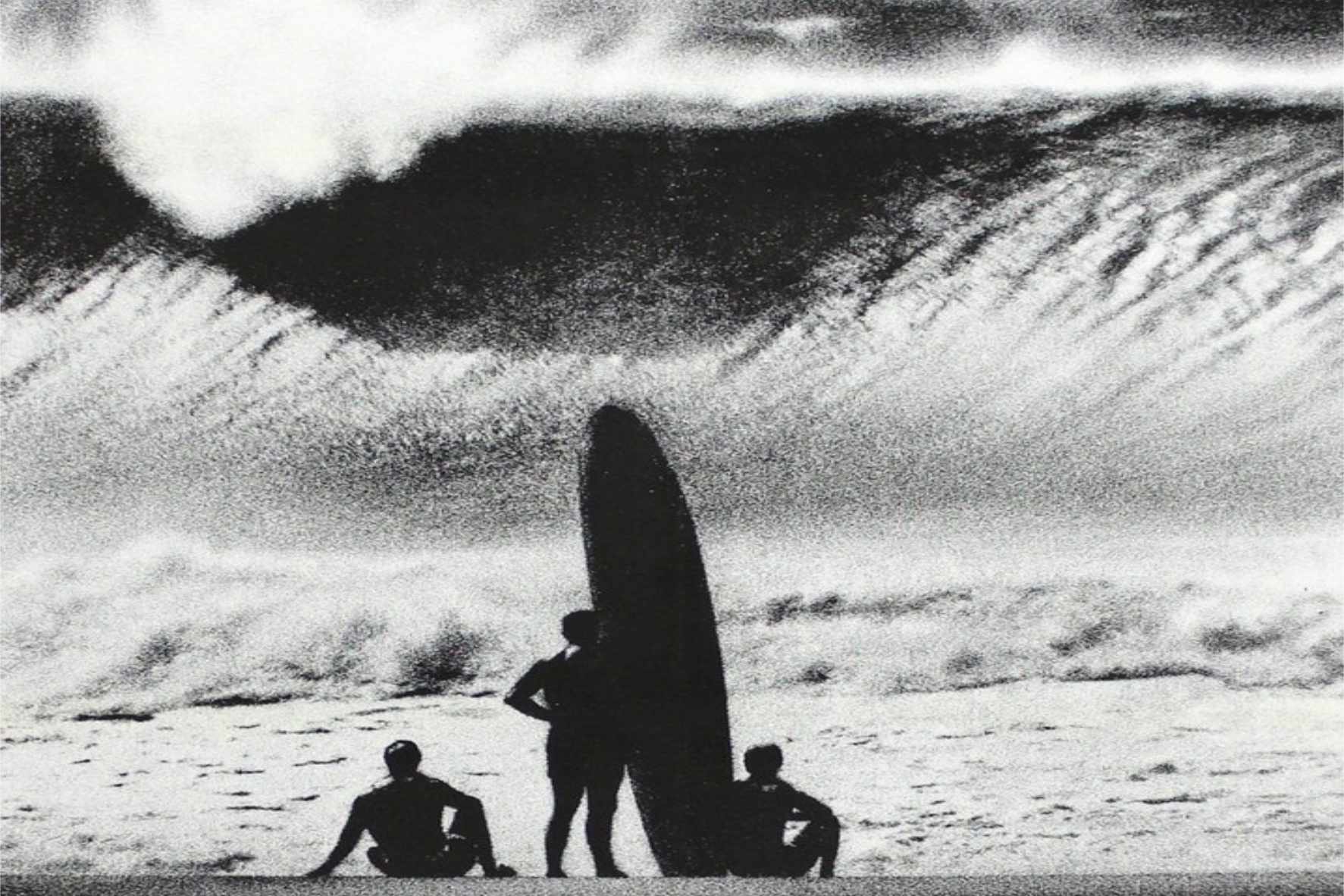 Tres surfers miran una ola enorme