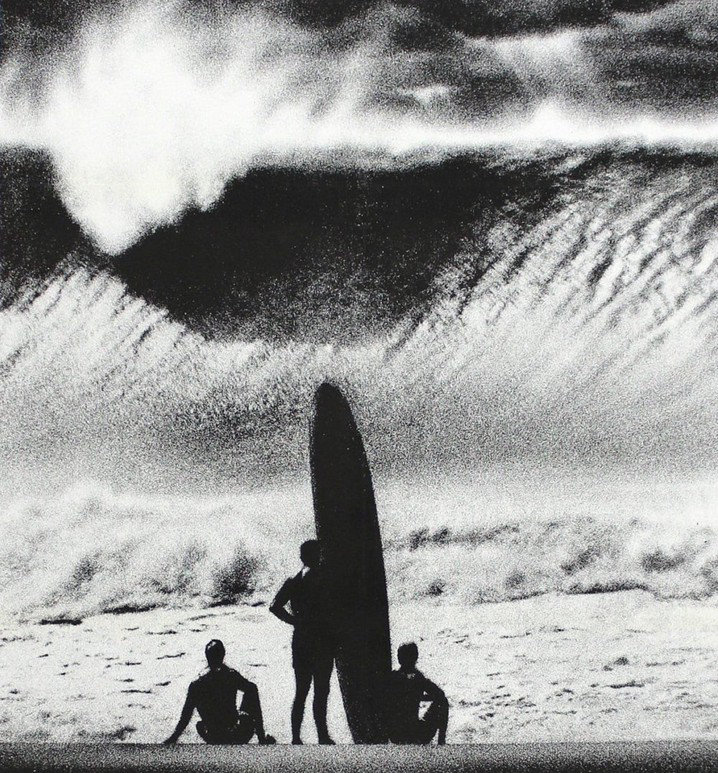 Tres surfers miran una ola enorme