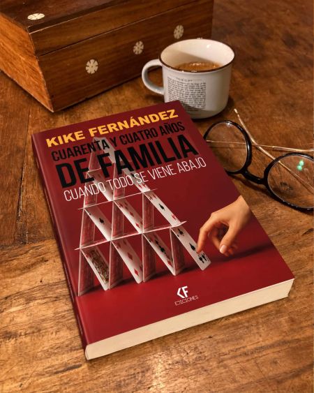 Portada del libro Cuarenta y cuatro años de familia, de Kike Fernández, sobre una mesa de madera junto a una taza de café y unas gafas.