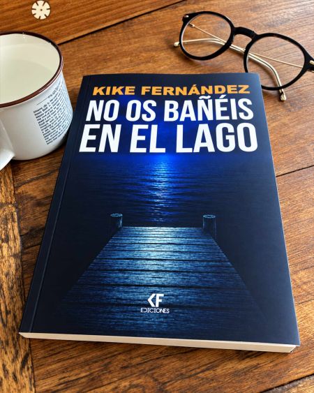 Portada del libro No os bañéis en el lago, de Kike Fernández, con un embarcadero sobre un lago oscuro, junto a una taza y unas gafas sobre una mesa de madera.